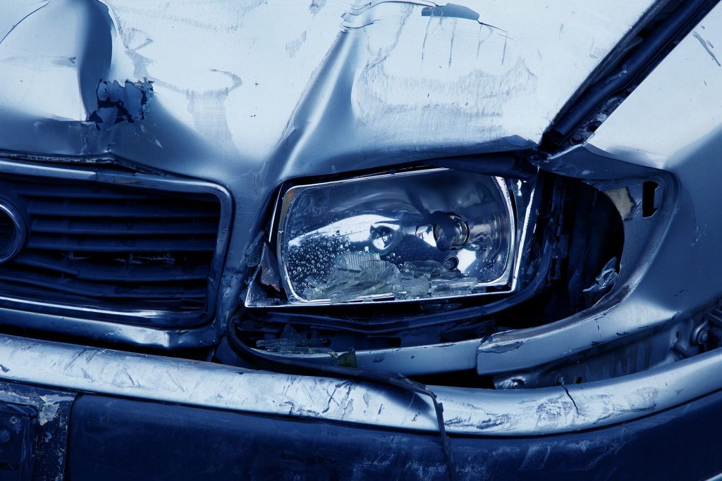 blue car with smashed front headlight close up