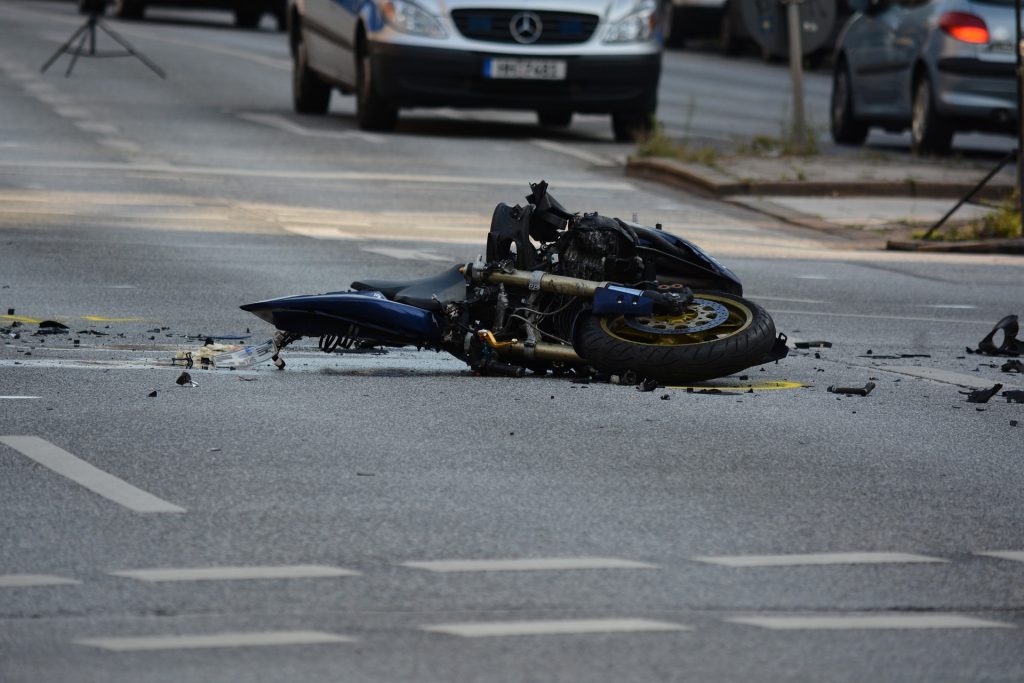 motorcycle on its side with broken pieces around following a crash