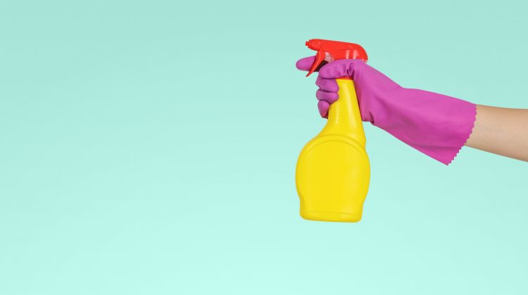 person holding yellow cleaning spray bottle