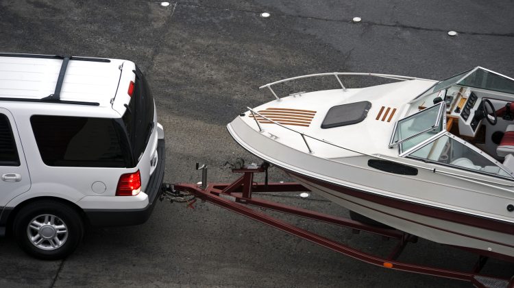 White SUV pulling white speed boat on trailer from above