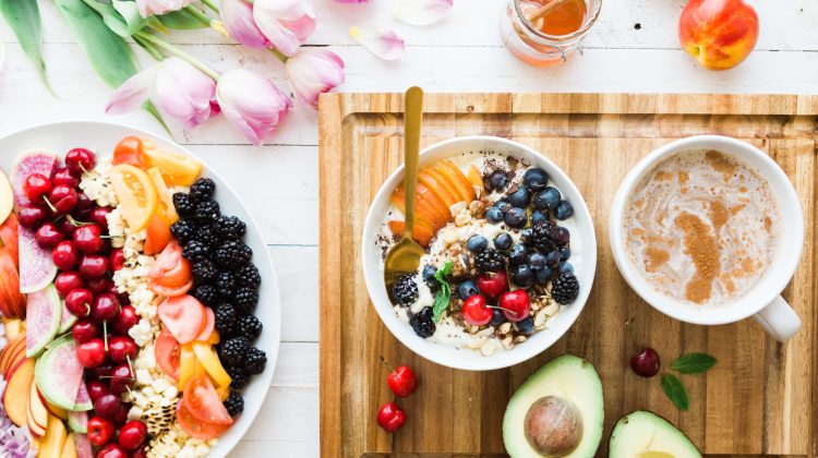 Collection of healthy foods like avocado, berries, and oatmeal placed on a white table