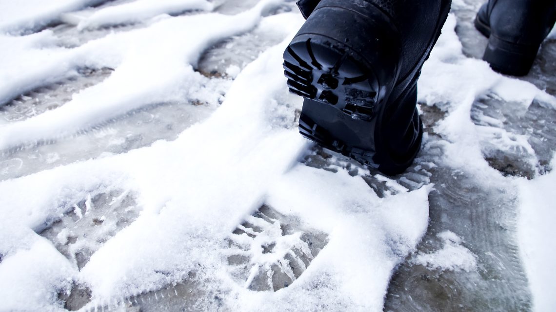 Walking through snow wearing snow shoes for traction.