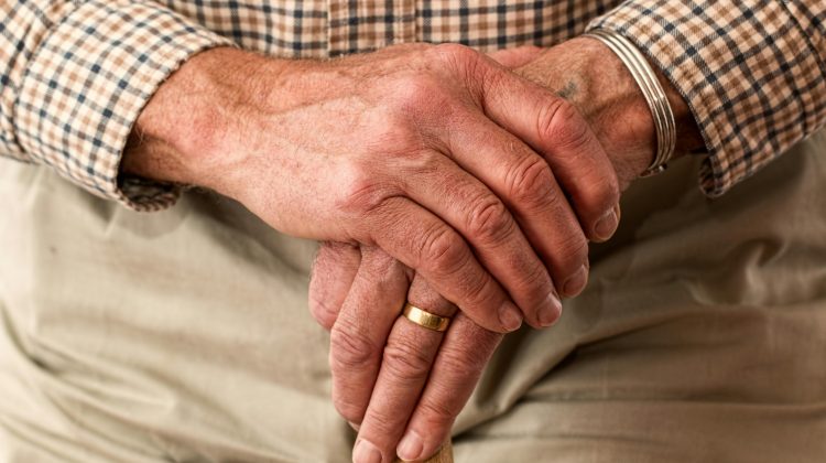 older adult's hands holding a walking cane