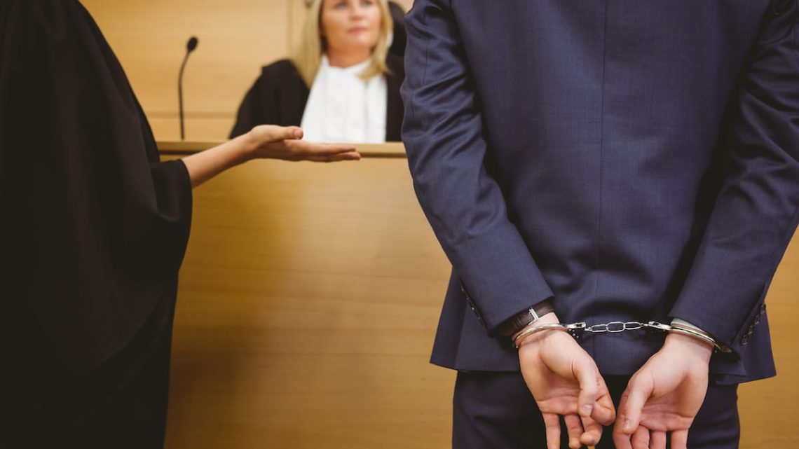 Man in handcuffs standing in a courtroom during a criminal case