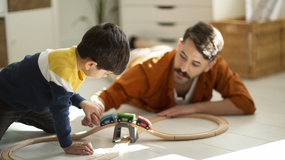 father and son happily playing with toy cars